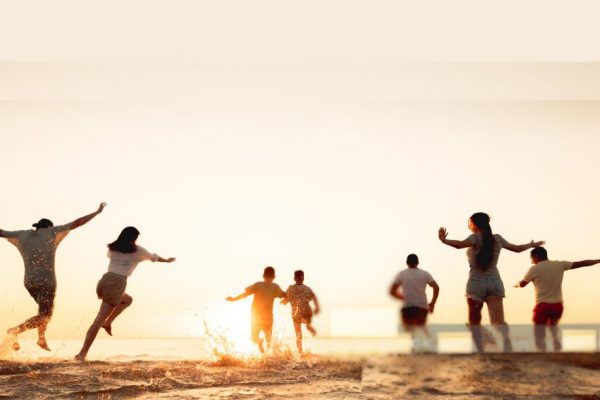 Big group of young friends or big family are having fun and run at sunset beach. Summer vacations concept